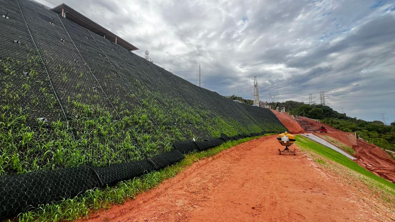Terraplenagem com talude protegido por geogrelha e vegetação